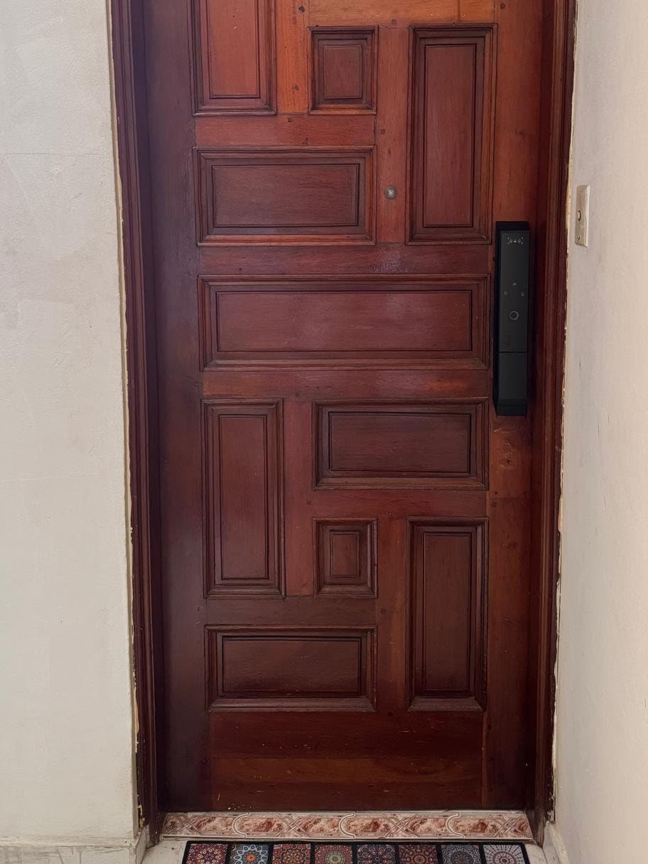 Cerradura inteligente indom instalada en una puerta antigua de madera maciza con molduras